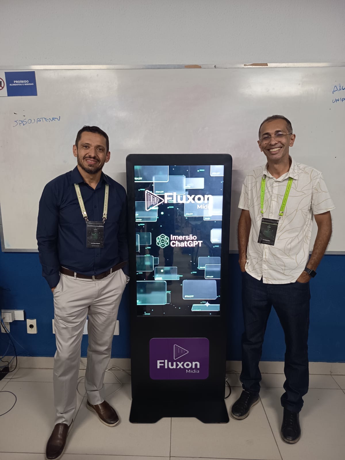 Dois participantes ao lado do painel da Imersão ChatGPT