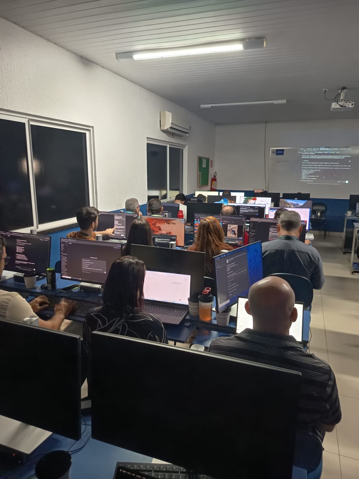 Participantes no laboratório de informática acompanhando a aula nos computadores